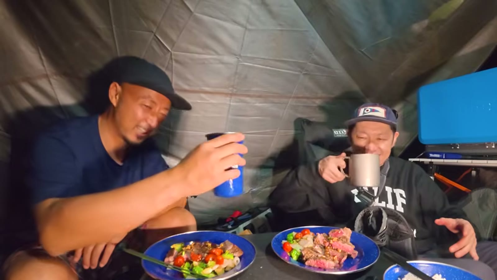 焚き火の前でハイボールを掲げて乾杯する