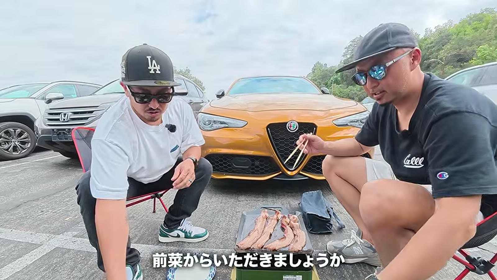 アルファロメオの隣でグリルを広げる二人